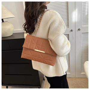 Détail du sac bandoulière matelassé marron avec finitions dorées sur pull