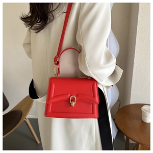 Close-up of a red box-shaped leather handbag with a gold ring lock and top handle