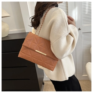 Détail du sac à bandoulière marron matelassé avec chaîne dorée et barre métallique chic