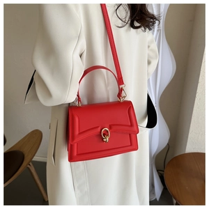 Detail of red leather crossbody bag featuring gold metal hardware and flap design