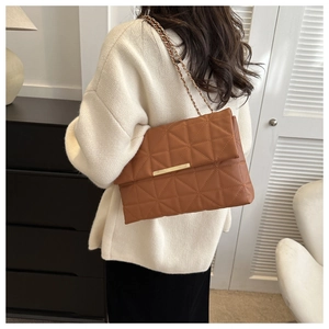 Détail d'un sac à bandoulière matelassé marron avec chaîne dorée et boucle en métal chic
