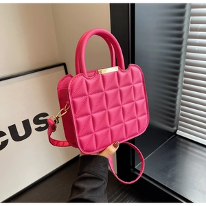 Detail of rose red quilted handbag featuring gold metal hardware and diamond pattern leather