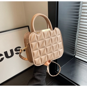 Detail of beige quilted handbag with geometric triangle pattern and gold hardware