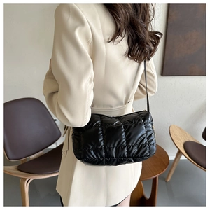 Detail of a black quilted cloud crossbody bag on a model wearing an off-white blazer