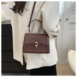 Detailed side view of deep coffee crossbody bag with golden buckle on a fashion model