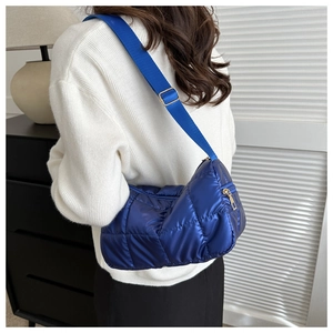 Detail of royal blue quilted nylon shoulder bag with fabric strap and golden metal buckle