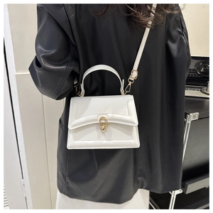 Detailed view of white leather handbag featuring a gold metal ring buckle and fine texture