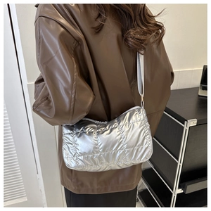 Detail of silver quilted crossbody bag with adjustable strap worn by model in leather jacket