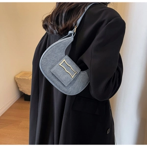 Vue détaillée du sac d'épaule en denim gris avec boucle métallique dorée ondulée