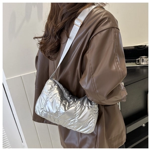 Close-up of quilted silver crossbody bag with adjustable strap and metallic finish