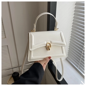 Detail of white quilted leather handbag with gold metal hardware and top handle strap