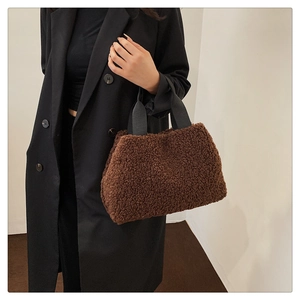 Detail einer braunen Teddy-Tote-Bag mit schwarzen Griffen an einem Model präsentiert
