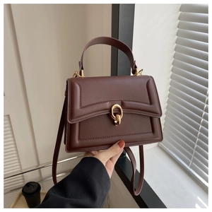 Detail of dark brown leather tote featuring a gold twist lock and fine stitching