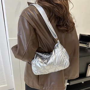 Silver quilted shoulder bag with shiny metallic finish and wide fabric strap on model