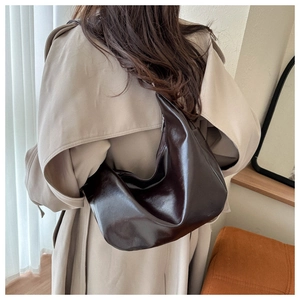 Macro shot of dark brown polished leather texture and soft folds on the hobo bag