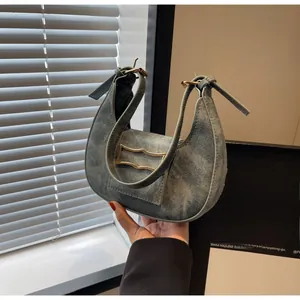 Détail d'un sac demi-lune en denim délavé avec boucle métallique dorée et rabat