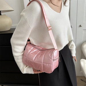 Pink quilted bubble puff shoulder bag with adjustable strap worn in a minimalist interior