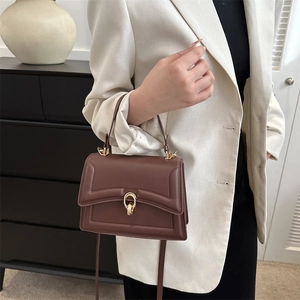 Deep brown leather handbag with gold ring buckle shown as crossbody on female model