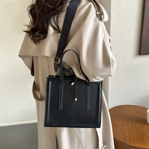 Minimalist black matte leather square tote bag with adjustable wide fabric strap on model