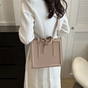 Chic beige rectangular crossbody bag with dual top handles and adjustable textile strap