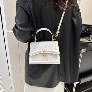 Chic white small crossbody bag with gold chain buckle worn over a black leather jacket