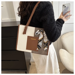 Close-up of a large tricolor tote bag with brown straps and silk scarf detail
