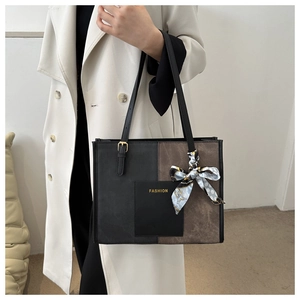 Detail of a large tote bag with black and brown panels and decorative blue silk scarf