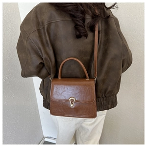 Detailed close-up of brown vintage leather crossbody bag with golden metal hardware buckle