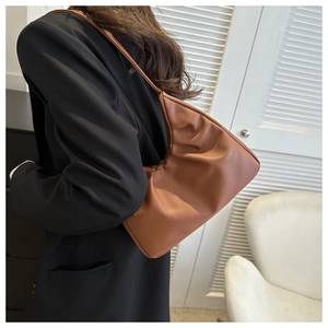 Close-up of caramel PU shoulder bag with pleated cloud design on a black blazer