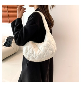 Dettaglio della borsa a mezzaluna bianca trapuntata indossata con un cappotto nero