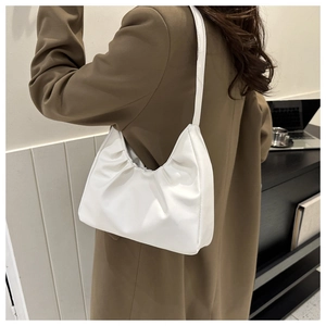 Close-up of stylish white pleated faux leather underarm bag worn with a brown blazer
