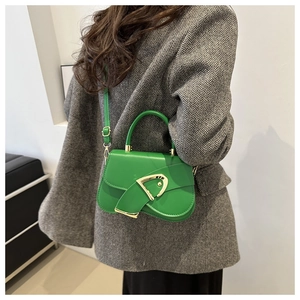 Close-up of bright green saddle bag featuring a bold gold buckle on wool blazer