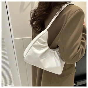 Close-up of white ruched shoulder bag texture on model wearing a brown blazer