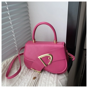 Detailed view of magenta saddle bag with golden D-clasp on white knit fabric