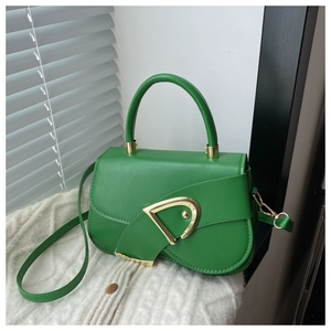 Close-up of bright green handbag featuring a geometric gold triangular metal clasp