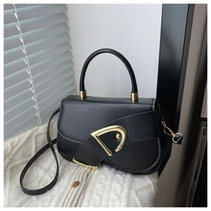 Detailed close-up of a black leather handbag with a gold D-shaped buckle on white knitwear