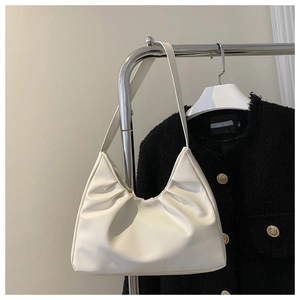 Close-up of white ruched faux leather underarm bag with elegant cloud pleats