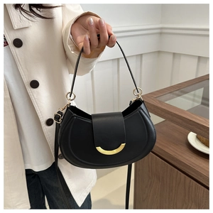 Dettaglio di una borsa a sella nera a mezzaluna con pelle martellata e chiusura oro