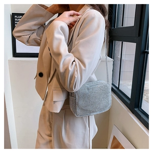 Détail du sac bandoulière en strass argenté avec chaîne sur un blazer beige