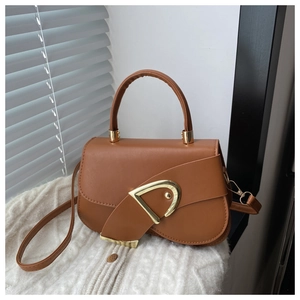 Detail of caramel brown saddle bag with golden D-shaped metal buckle and smooth texture