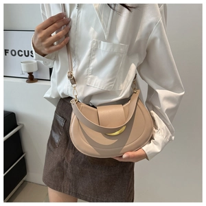 Dettaglio borsa a spalla beige a mezzaluna con fibbia dorata e doppia opzione di tracolla