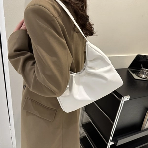 Chic white pleated shoulder bag with minimalist cloud design on a model in a brown suit