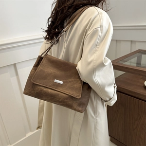 Brown vintage suede tote bag with chain strap shown on a model in beige trench coat