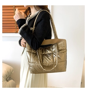 Detailed close-up of metallic gold quilted tote bag with square stitching patterns