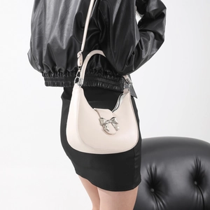 Sac hobo blanc crème avec boucle en forme de nœud argenté porté par un mannequin