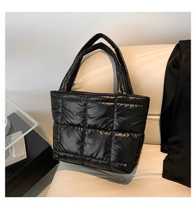 Detailed view of black quilted tote bag with glossy finish on a minimalist sofa