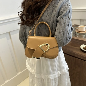 Minimalist camel leather crossbody bag with a gold D-ring buckle on a model