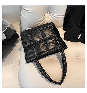 Detail of black quilted puffer tote bag showing glossy nylon fabric and padded handles