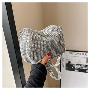 Close-up of sparkling silver rhinestone handbag held against a minimalist background