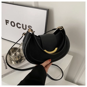 Dettaglio di borsa hobo a mezzaluna in pelle nera con fibbia dorata e texture liscia